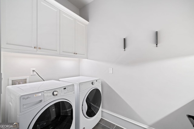 washroom with cabinets, separate washer and dryer, and dark tile patterned floors