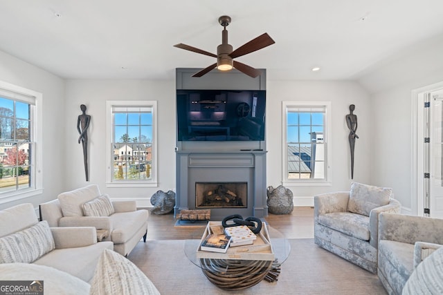 living room with hardwood / wood-style floors, ceiling fan, and vaulted ceiling