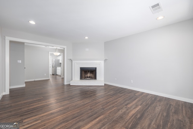 unfurnished living room with a fireplace and dark wood-type flooring