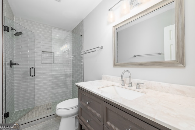 bathroom with vanity, toilet, and a shower with door