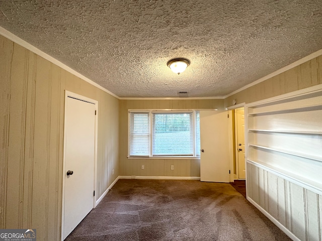 spare room featuring a textured ceiling, dark carpet, and crown molding