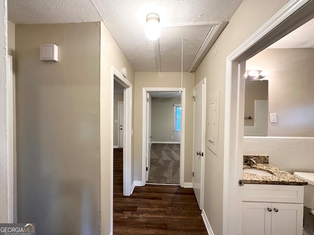 corridor with a textured ceiling, dark wood-type flooring, and sink