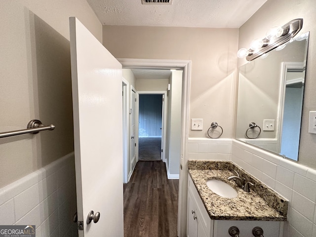1737 Mckenzie Dr, Decatur, GA 30032 - bathroom featuring wood finished floors, vanity, tile walls, and a textured ceiling