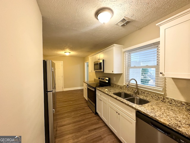 kitchen featuring appliances with stainless steel finishes, dark hardwood / wood-style flooring, light stone counters, sink, and white cabinets