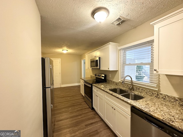1737 Mckenzie Dr, Decatur, GA 30032 - kitchen featuring appliances with stainless steel finishes, a textured ceiling, white cabinets, dark wood-style floors, and light stone counters