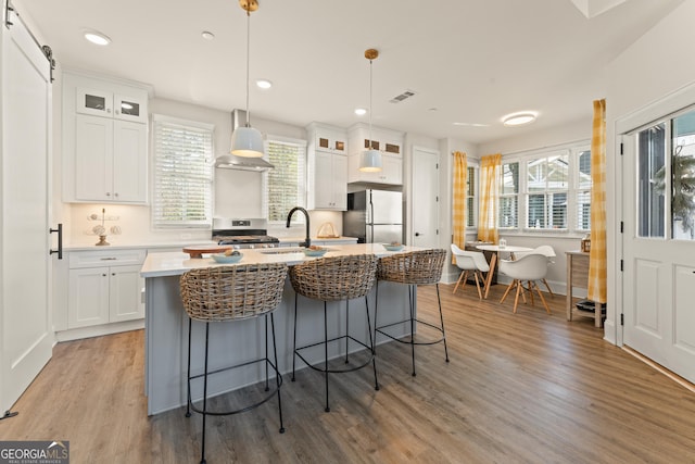 kitchen featuring glass insert cabinets, appliances with stainless steel finishes, light countertops, and pendant lighting