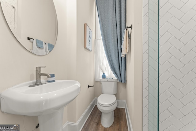 bathroom featuring baseboards, a sink, toilet, and wood finished floors