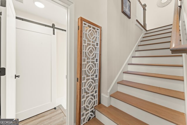 stairs featuring a barn door and wood finished floors