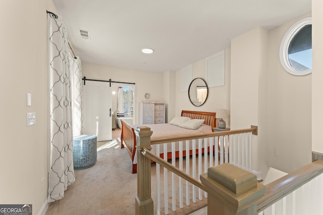 bedroom with a barn door, visible vents, and light colored carpet