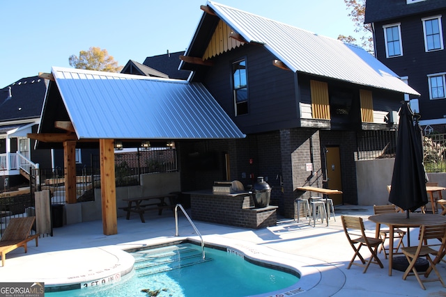 rear view of house featuring brick siding, a patio area, metal roof, fence, and a community pool