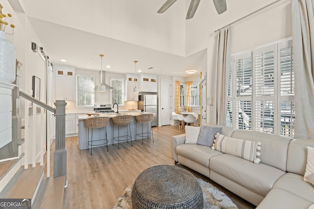 living area featuring light wood finished floors, recessed lighting, a towering ceiling, a ceiling fan, and stairs