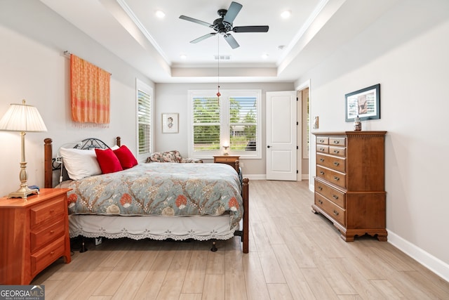 bedroom with ceiling fan, a raised ceiling, crown molding, and light hardwood / wood-style flooring