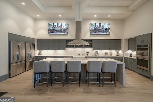 kitchen featuring appliances with stainless steel finishes, light hardwood / wood-style floors, a kitchen breakfast bar, and a spacious island