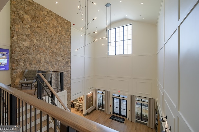 stairs with wood-type flooring, a fireplace, and high vaulted ceiling