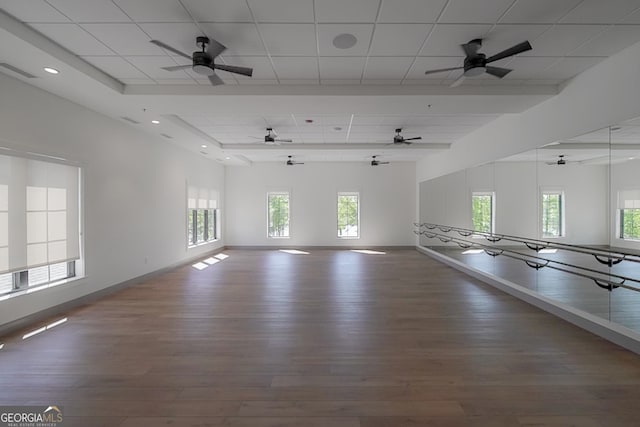 unfurnished room with a wealth of natural light, dark hardwood / wood-style flooring, and a drop ceiling