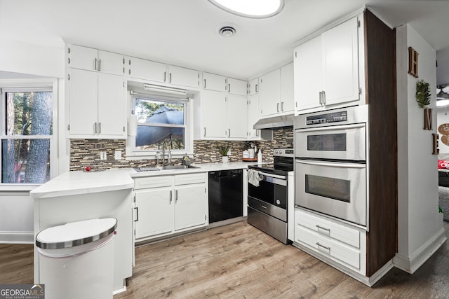 kitchen with tasteful backsplash, stainless steel appliances, sink, white cabinets, and light hardwood / wood-style floors