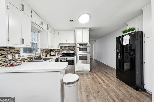 kitchen with sink, light hardwood / wood-style flooring, decorative backsplash, white cabinetry, and stainless steel appliances