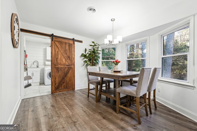 dining room featuring a barn door, sink, dark wood-type flooring, and washer / clothes dryer