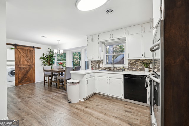 kitchen featuring washer / clothes dryer, a barn door, white cabinets, black dishwasher, and light hardwood / wood-style floors