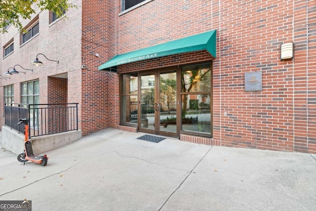 property entrance featuring a patio and brick siding