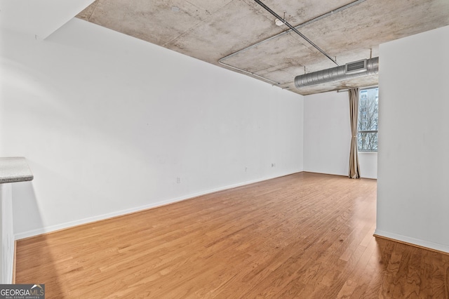 unfurnished room featuring wood finished floors, visible vents, and baseboards