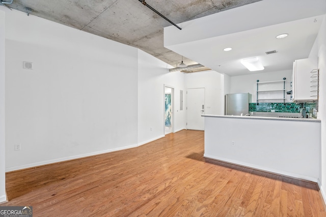 kitchen featuring light wood-style flooring, white cabinetry, freestanding refrigerator, decorative backsplash, and open shelves