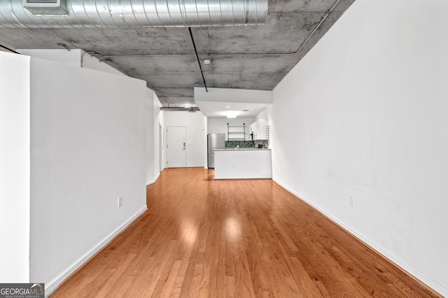 unfurnished living room with light wood-type flooring, visible vents, and baseboards