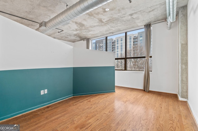 unfurnished room with baseboards, a city view, and wood finished floors