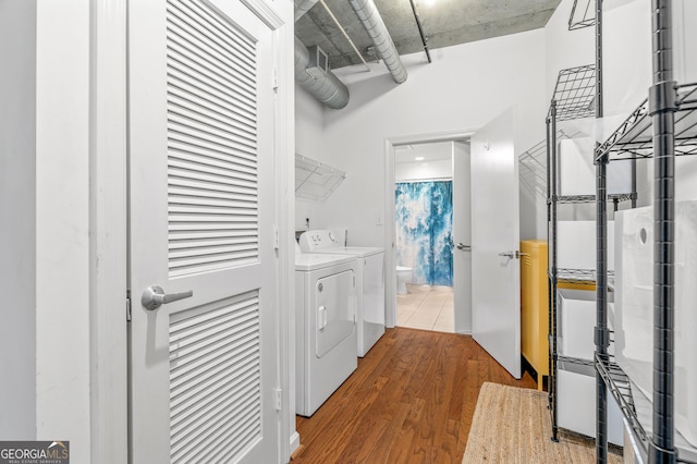 laundry area with laundry area, washer and clothes dryer, and wood finished floors