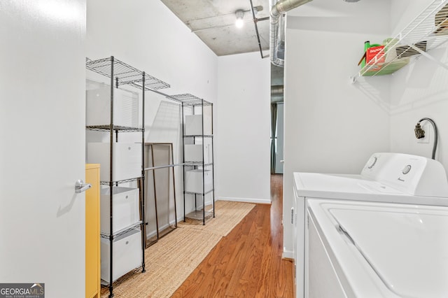 laundry area with laundry area, baseboards, washer and clothes dryer, and light wood finished floors