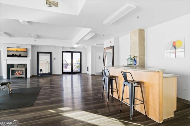 interior space featuring a warm lit fireplace, open floor plan, visible vents, and a kitchen breakfast bar