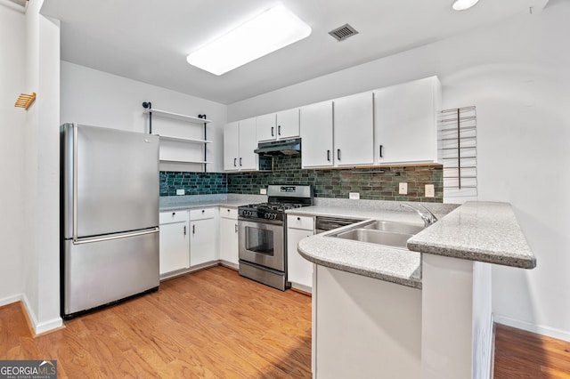 kitchen featuring visible vents, a peninsula, stainless steel appliances, under cabinet range hood, and a sink