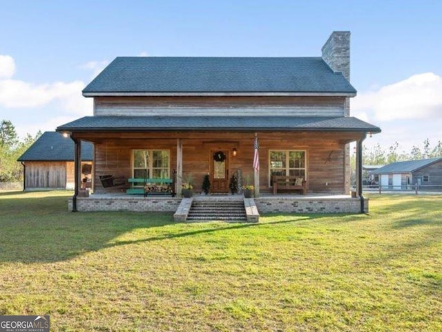 rear view of property with covered porch and a yard