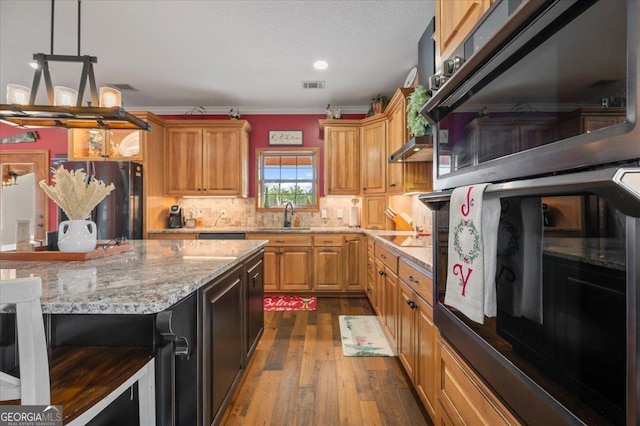 kitchen with dark wood-type flooring, black fridge, ornamental molding, tasteful backsplash, and decorative light fixtures