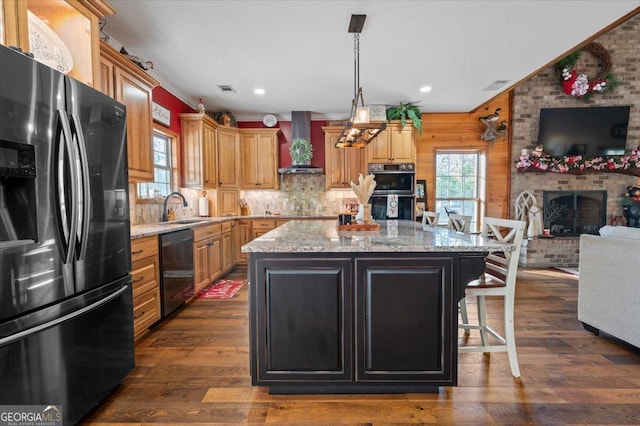 kitchen with a center island, wall chimney exhaust hood, dark hardwood / wood-style flooring, black appliances, and ornamental molding