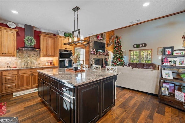 kitchen with ornamental molding, dark hardwood / wood-style flooring, a center island, and wall chimney exhaust hood