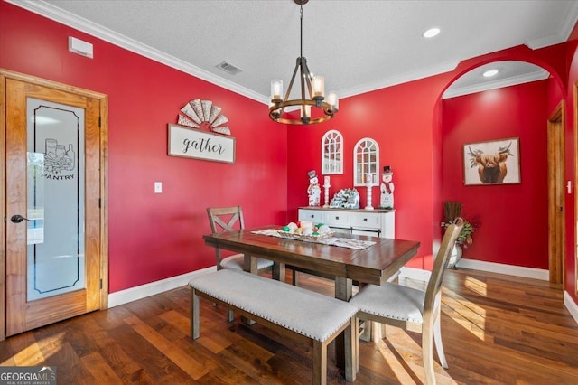 dining room with a chandelier, a textured ceiling, dark hardwood / wood-style flooring, and ornamental molding