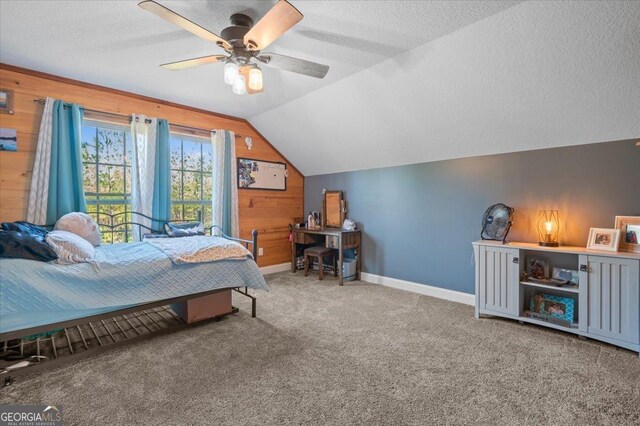 carpeted bedroom with a textured ceiling, lofted ceiling, ceiling fan, and wooden walls