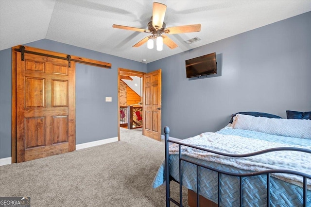 bedroom with carpet, ceiling fan, a barn door, and lofted ceiling