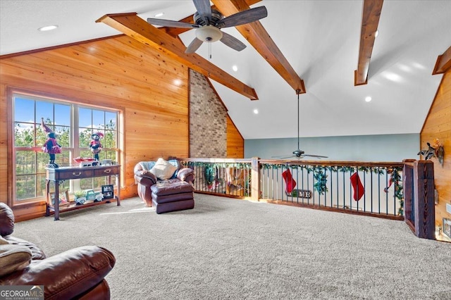 living area with beam ceiling, carpet flooring, ceiling fan, high vaulted ceiling, and wood walls