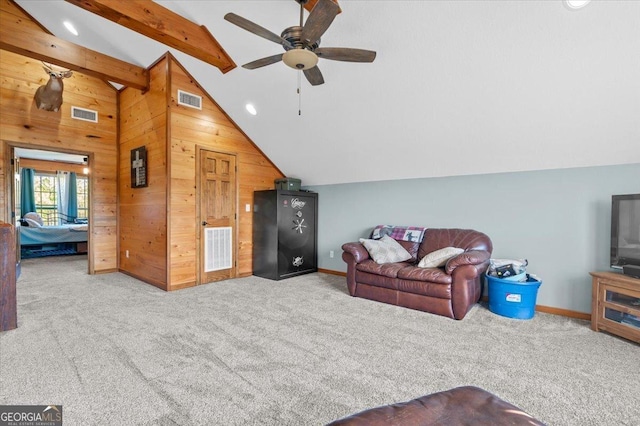 living room with carpet flooring, lofted ceiling with beams, ceiling fan, and wooden walls