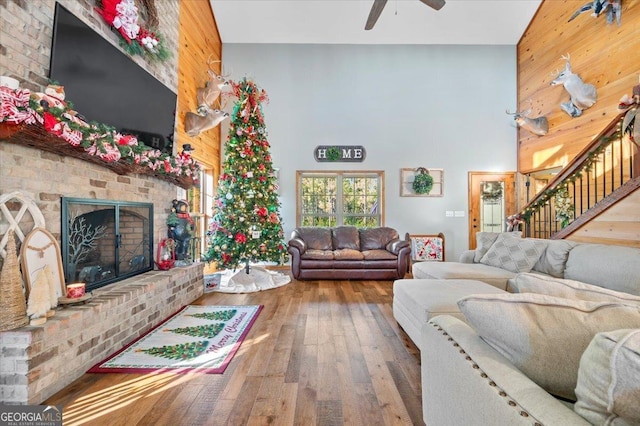 living room with hardwood / wood-style floors, high vaulted ceiling, ceiling fan, and a brick fireplace