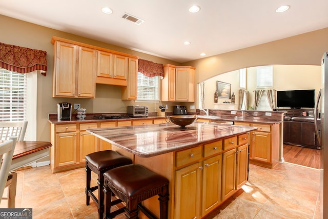 kitchen featuring kitchen peninsula, a kitchen breakfast bar, a center island, and plenty of natural light