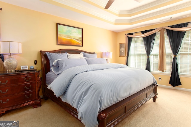 carpeted bedroom with a raised ceiling, ceiling fan, and ornamental molding