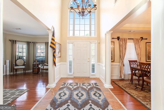 foyer entrance featuring crown molding, dark hardwood / wood-style flooring, a high ceiling, and a notable chandelier