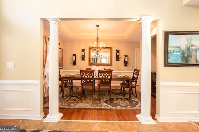 dining room with a tray ceiling, crown molding, wood-type flooring, and a notable chandelier