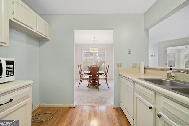 kitchen featuring light wood-type flooring, white appliances, decorative light fixtures, and sink