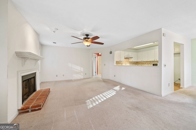 unfurnished living room featuring ceiling fan, a fireplace, and light colored carpet