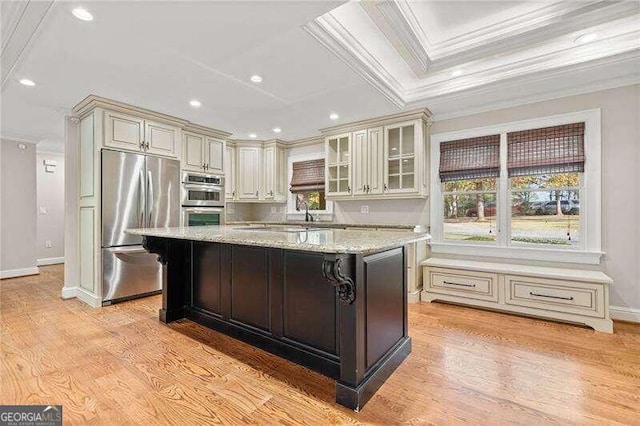 kitchen with a center island, light stone counters, light wood-type flooring, and stainless steel appliances