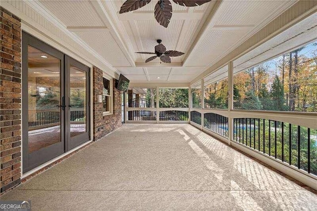 unfurnished sunroom with ceiling fan, a healthy amount of sunlight, and coffered ceiling